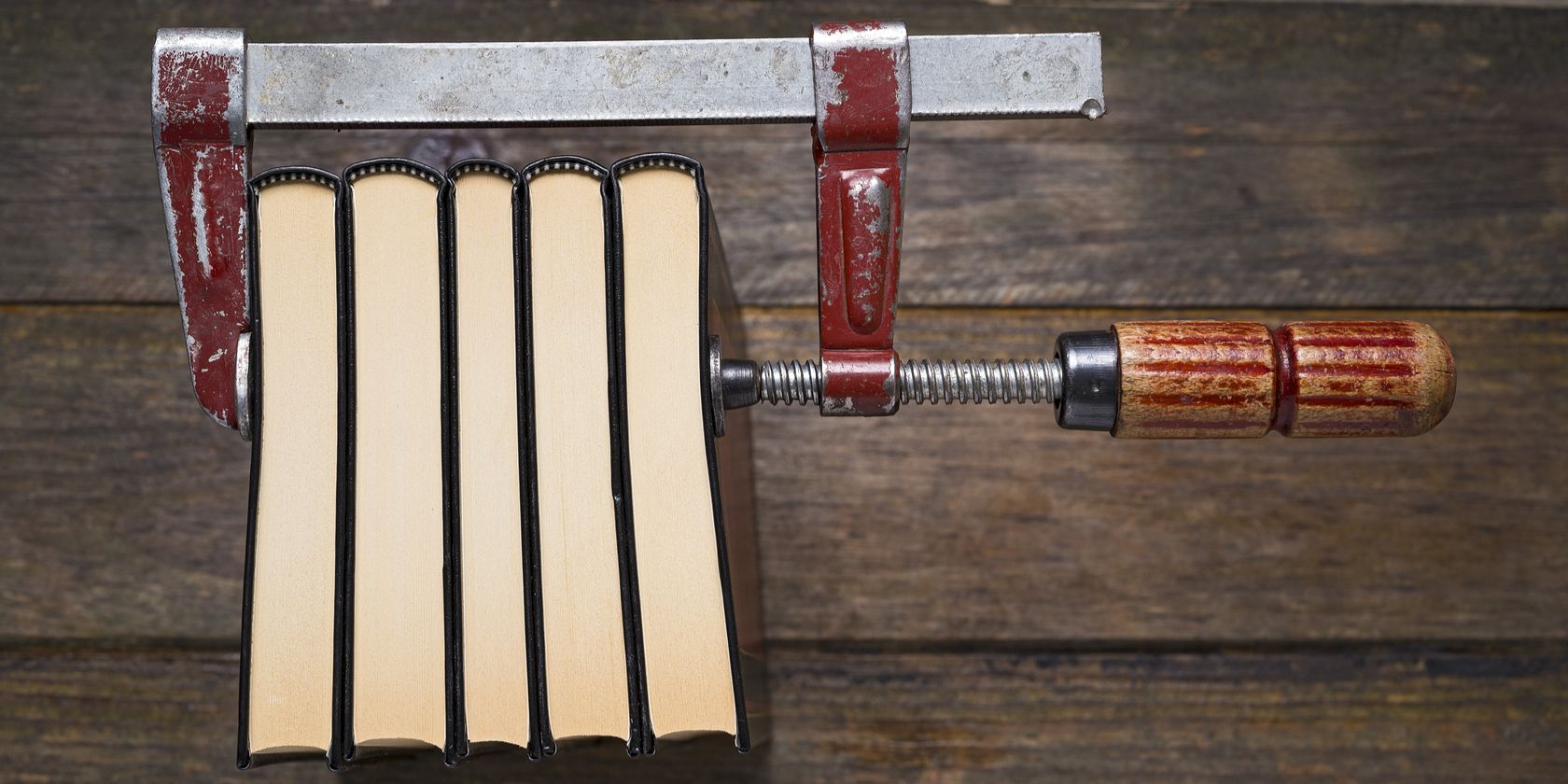 Clamp holding books together on a wooden table
