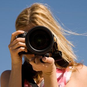 Woman Holding an SLR Still Picture Camera towards the viewer