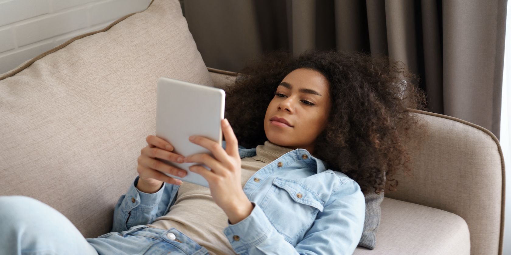 Woman laying on a couch reading a digital book