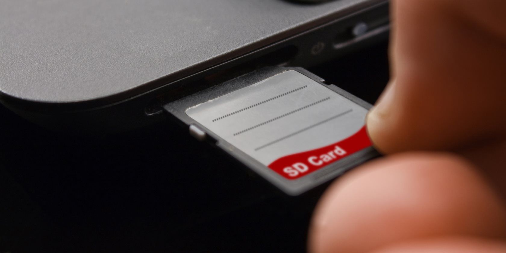 Hand inserting SD card into laptop