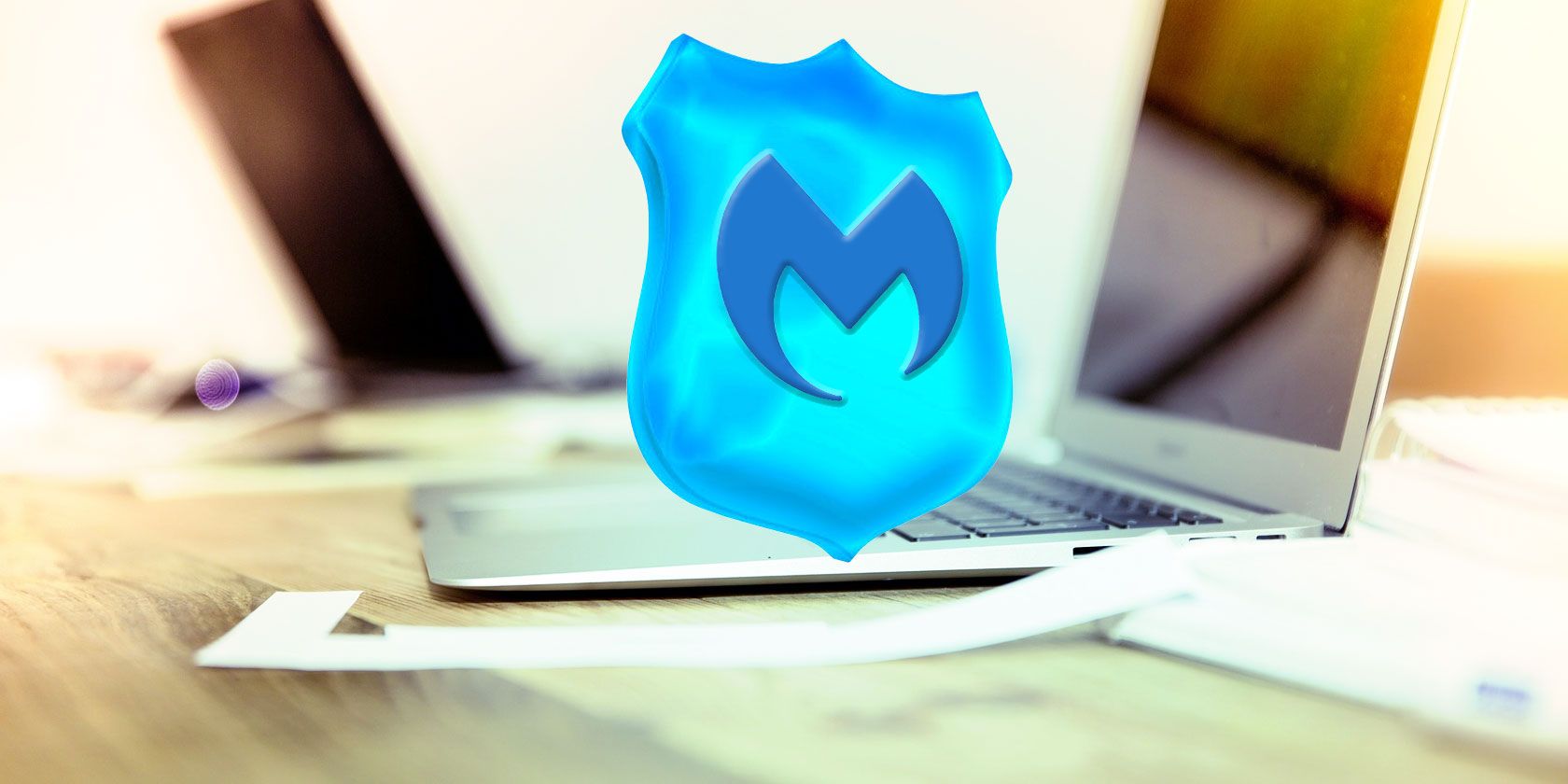 Malwarebytes logo on a blue shield, showing over a laptop