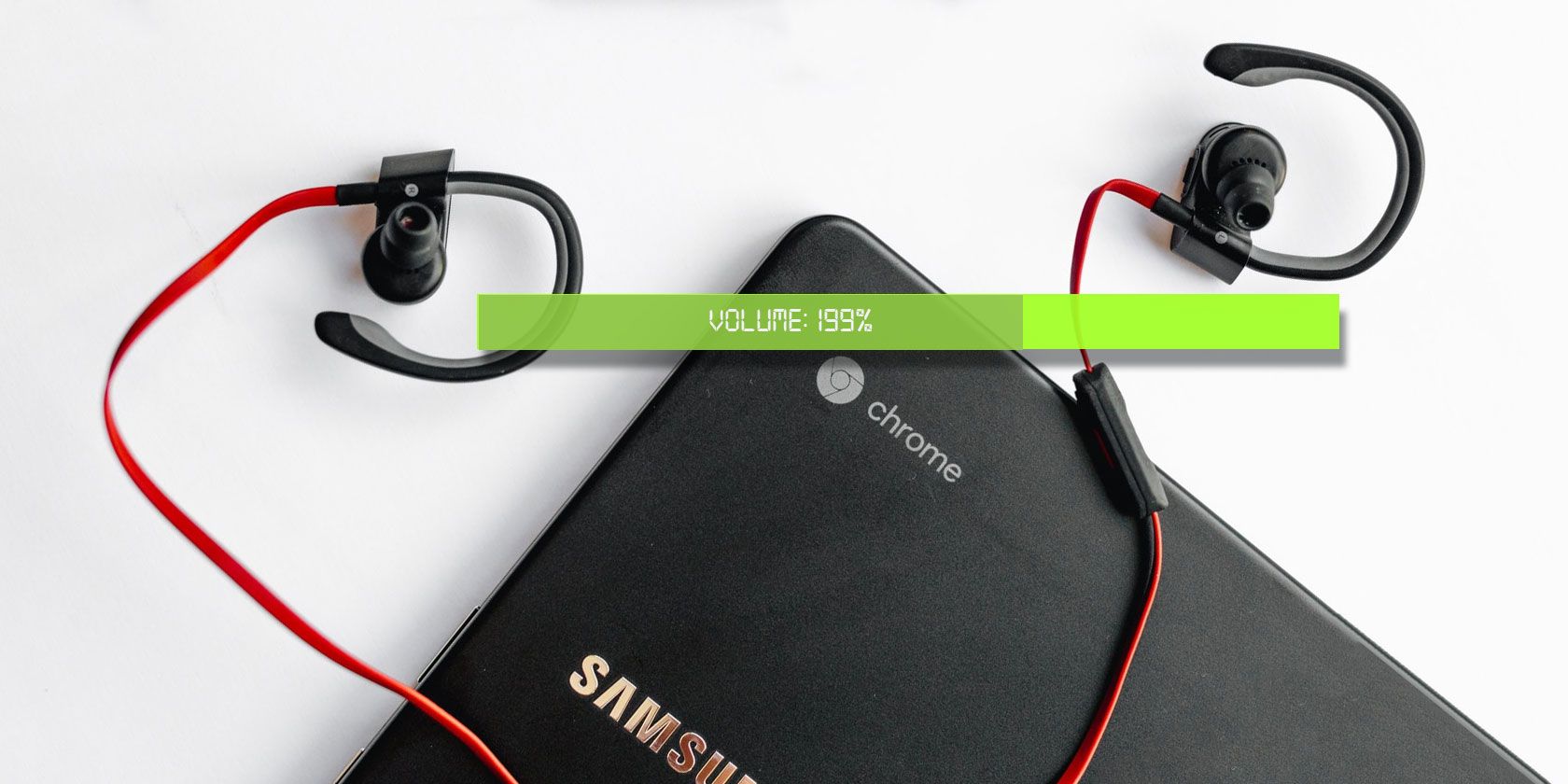 A pair of earphones lies on top of a closed chromebook with an illustration of a volume bar superimposed