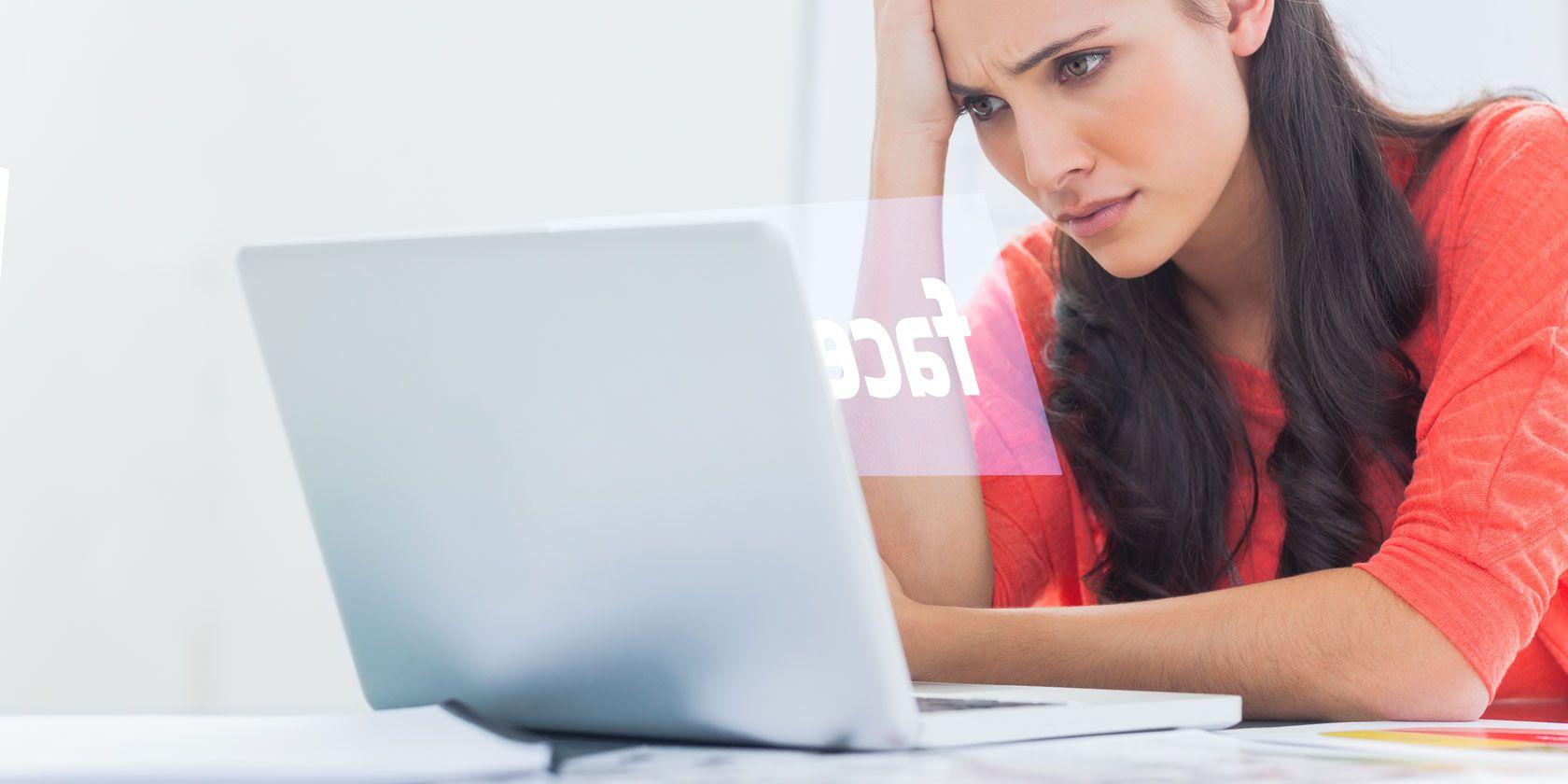Woman looking frustrated at laptop showing Facebook logo