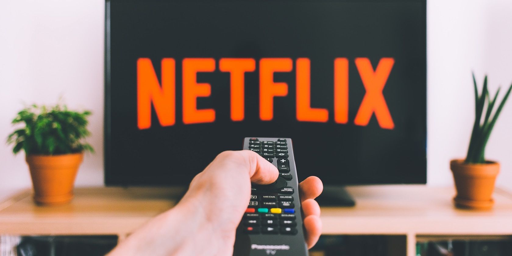 Hand pointing remote at Netflix on TV