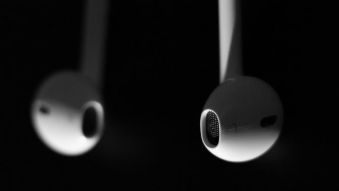 AirPods hanging upside down in front of black background