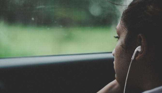 Woman listening to Apple EarPods looking out a window