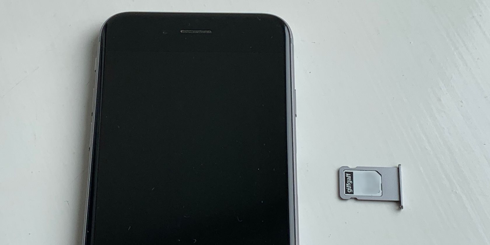 SIM card in tray next to iPhone2 - Come rimuovere una scheda SIM da un iPhone