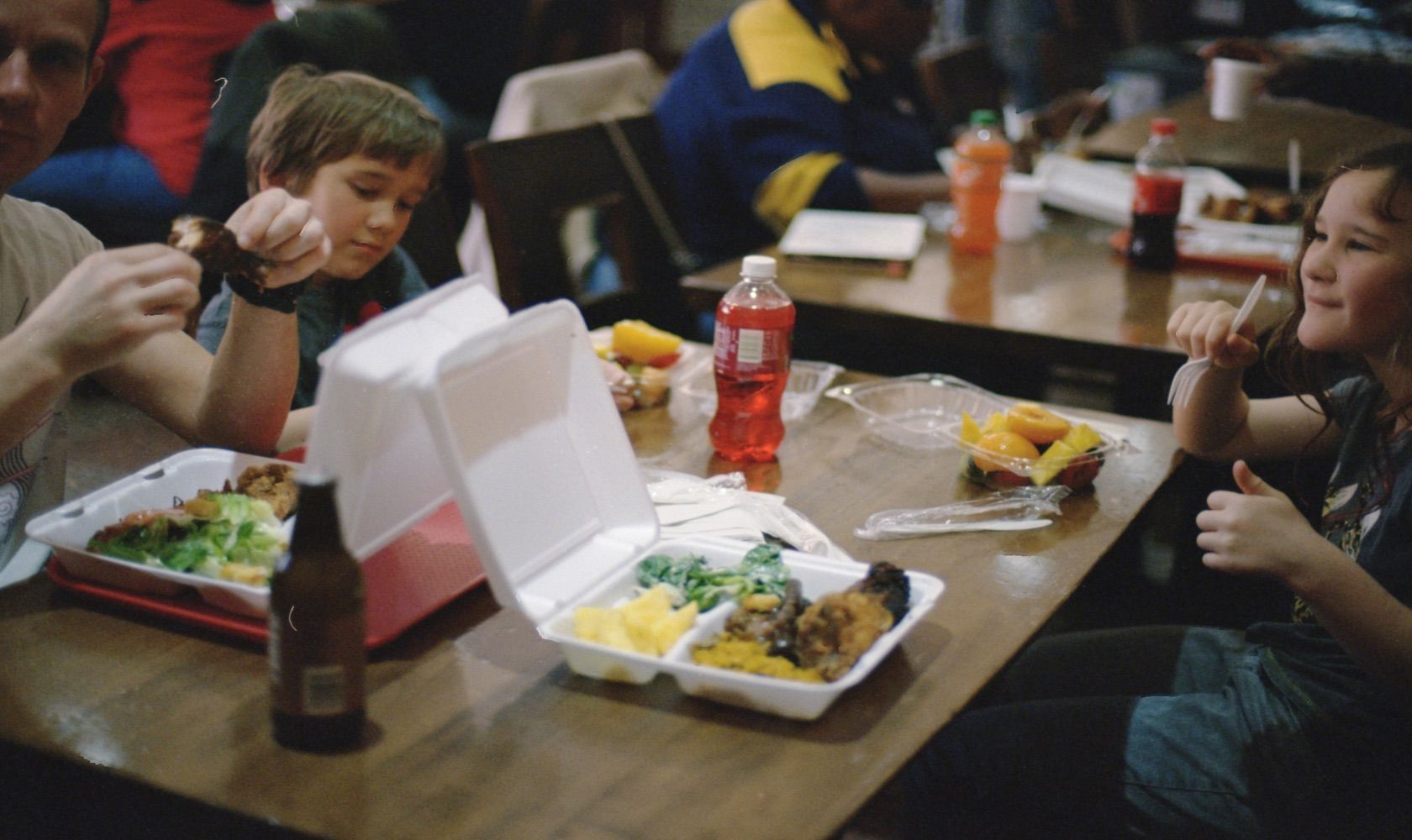 adult and two children eating food from takeout containers
