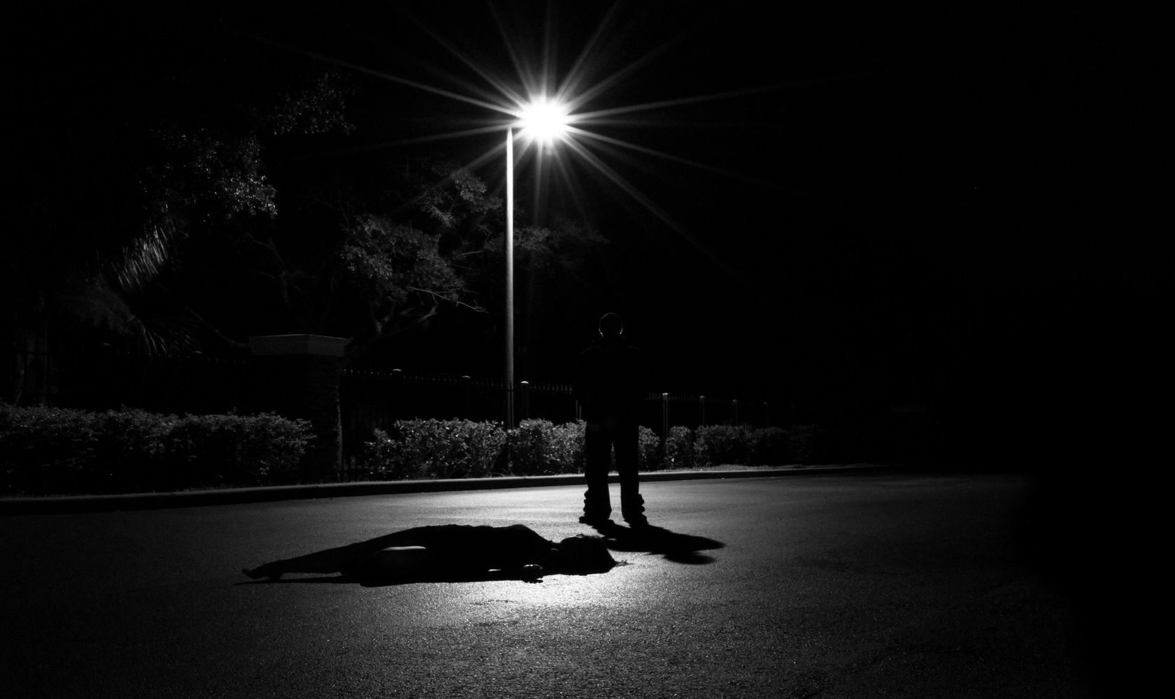 Person outside standing in the dark above another person