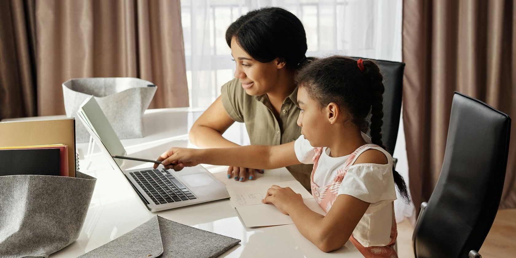 Child sitting in front of a laptop with a parent