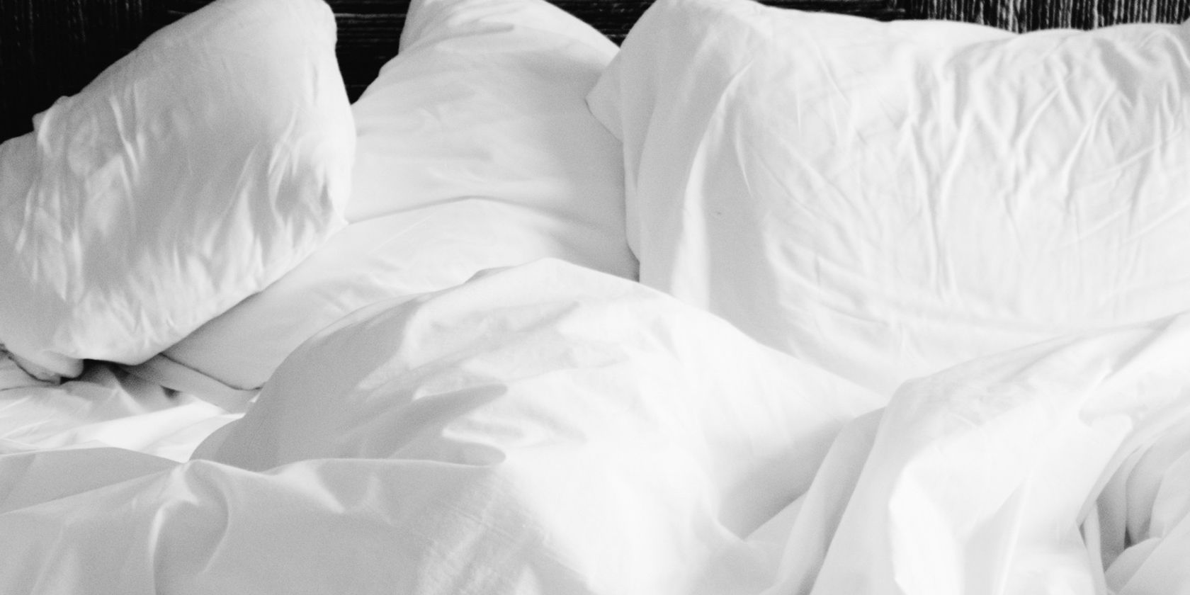 Fluffly white pillows strewn across a messy bed.