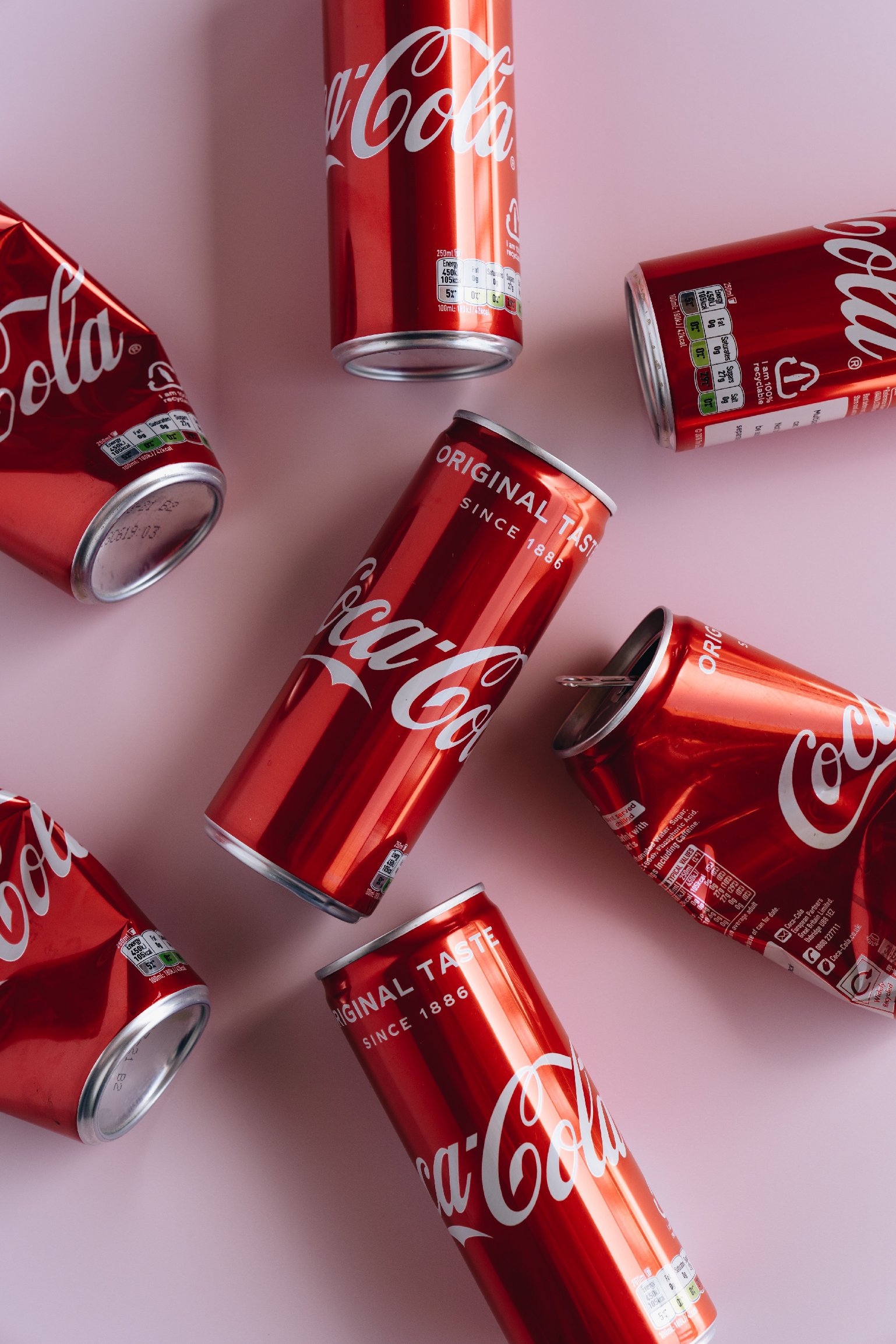 Scattered Coca-Cola cans on pink BG