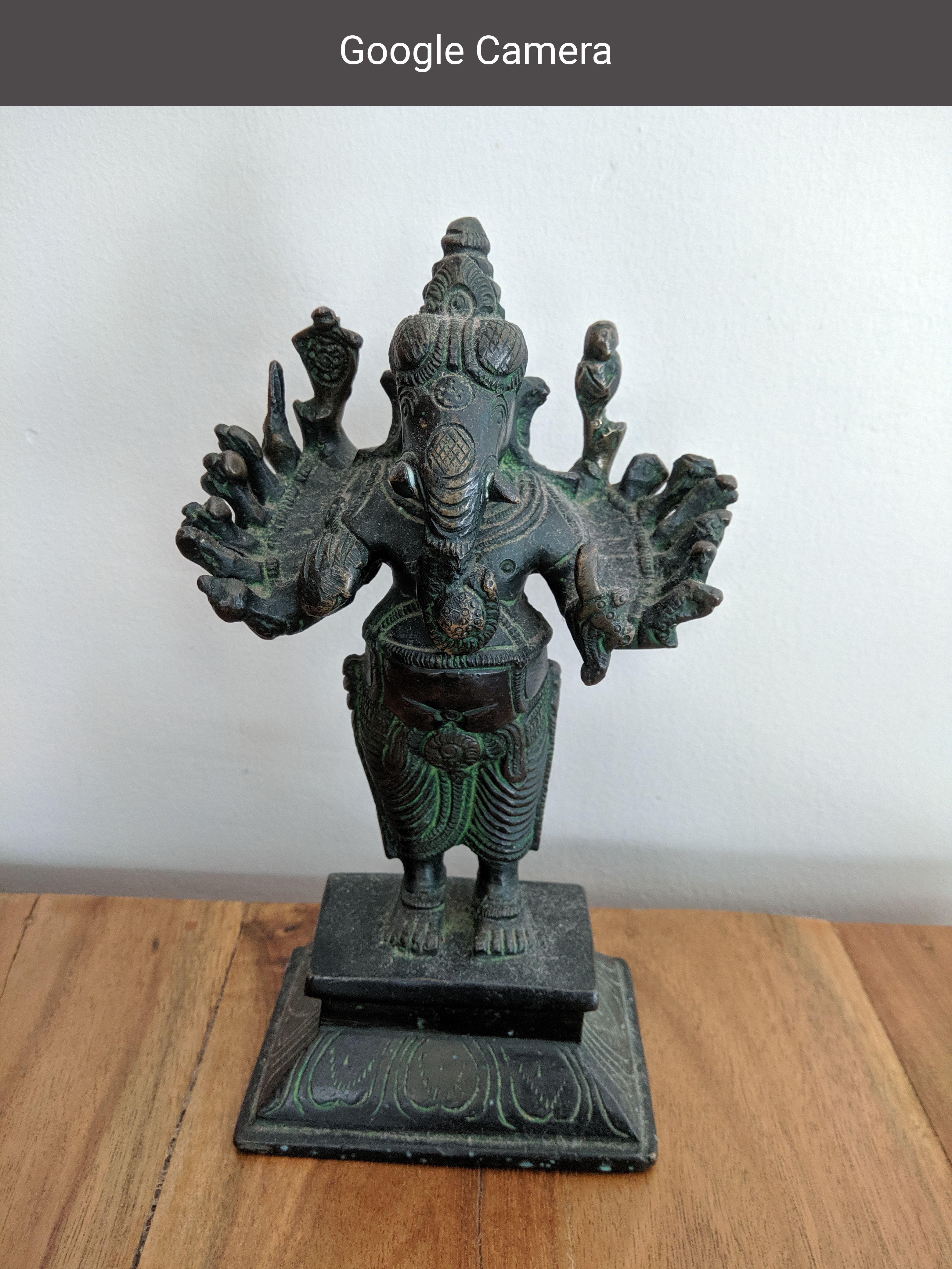 A metallic statue of Lord Ganesha placed on a wooden surface