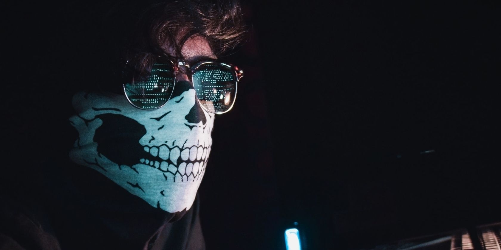 Man wearing a skull mask using a computer