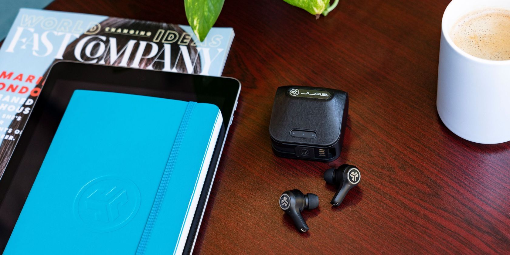 JLab Audio Epic Air ANC TWS earphones lying on a desk, next to charging case