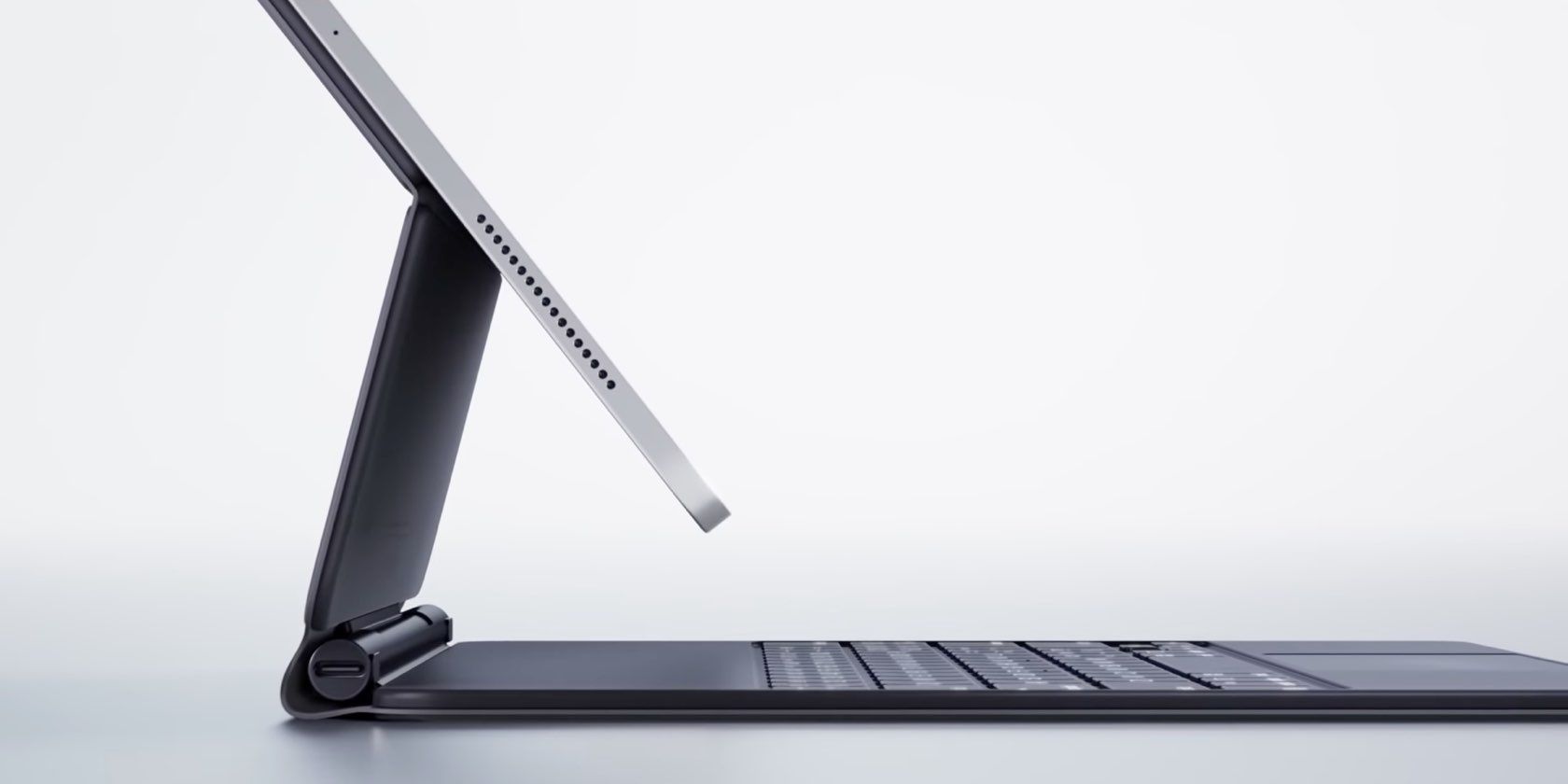 A profile view of a 12.9-inch iPad Pro (2018 model) suspended mid-air on a Magic Keyboard