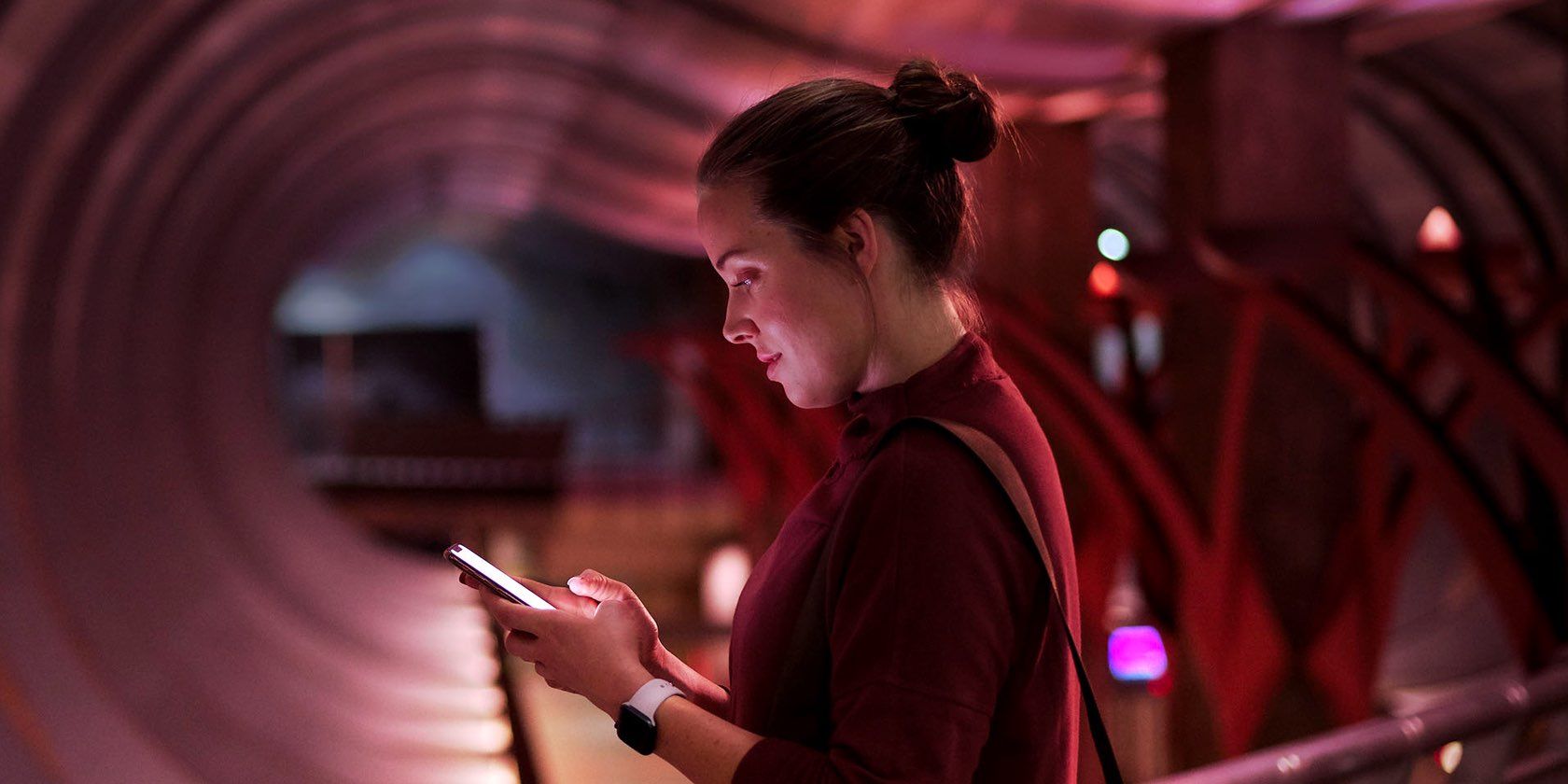 A woman wearing an Apple Watch and holding an iPhone in her hand while typing an iMessage text in Messages