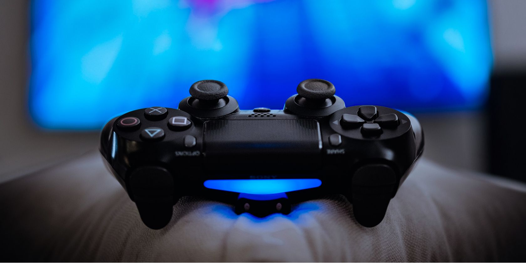 PS4 controller on pillow in front of a TV