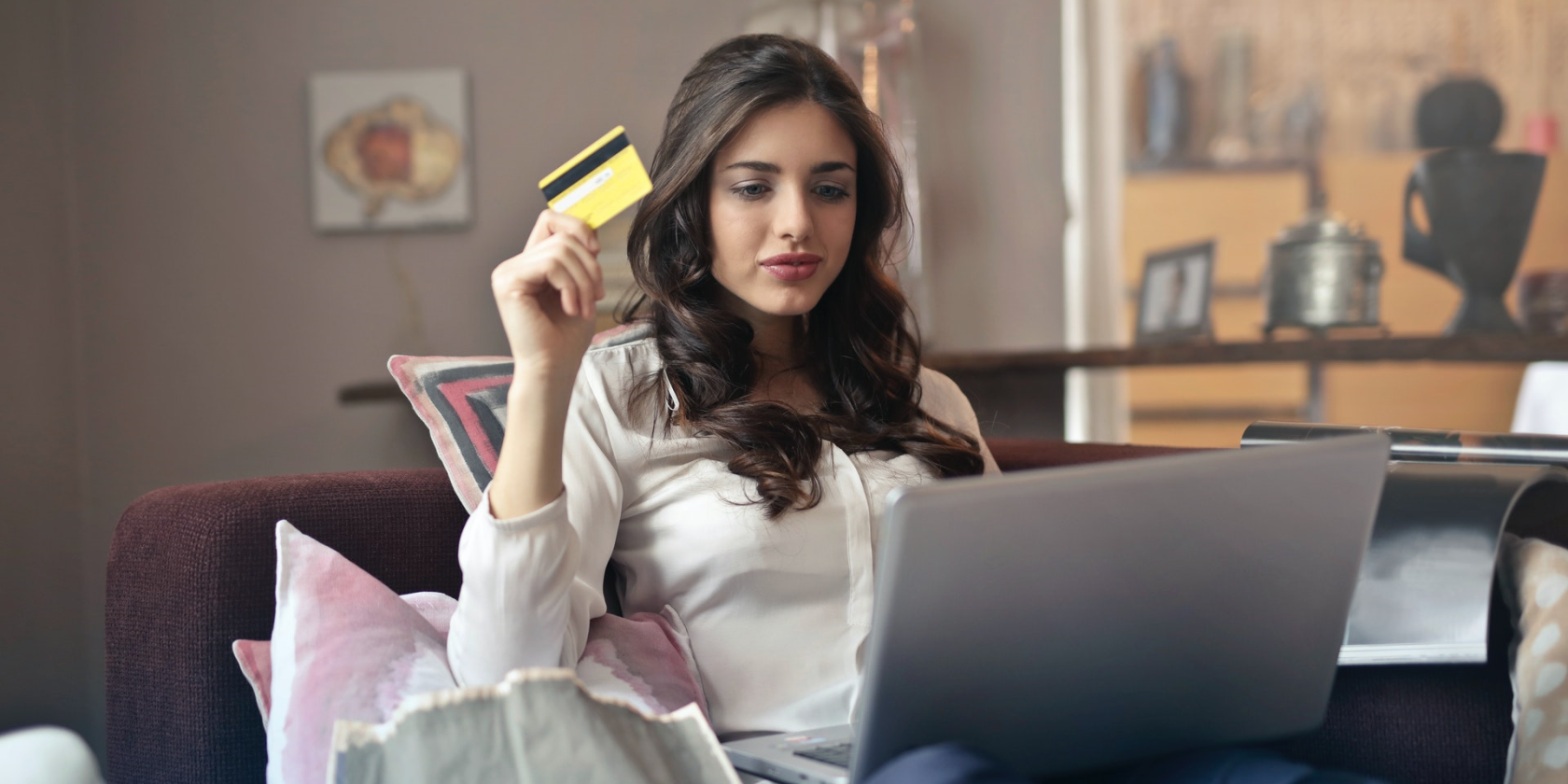 Woman holding a credit card and shopping on her laptop