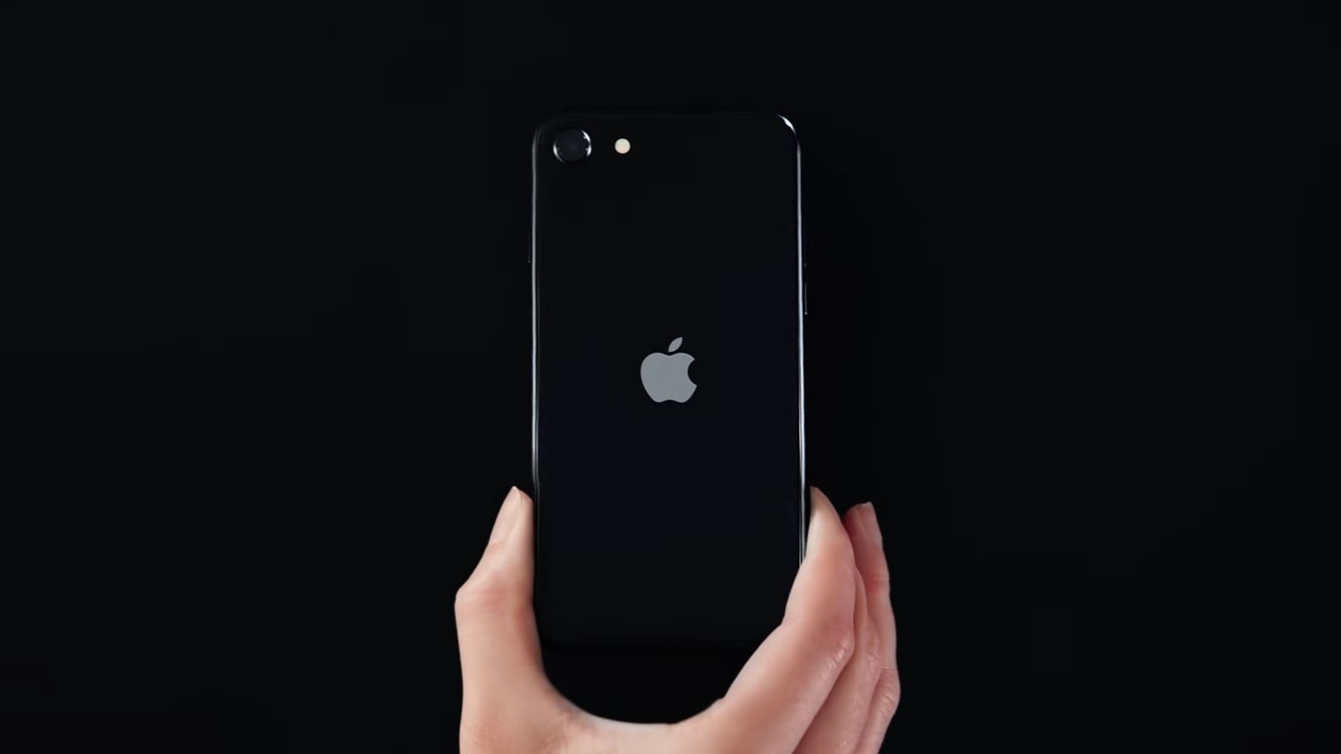 A still from an Apple ad showing a black iPhone SE (2020)