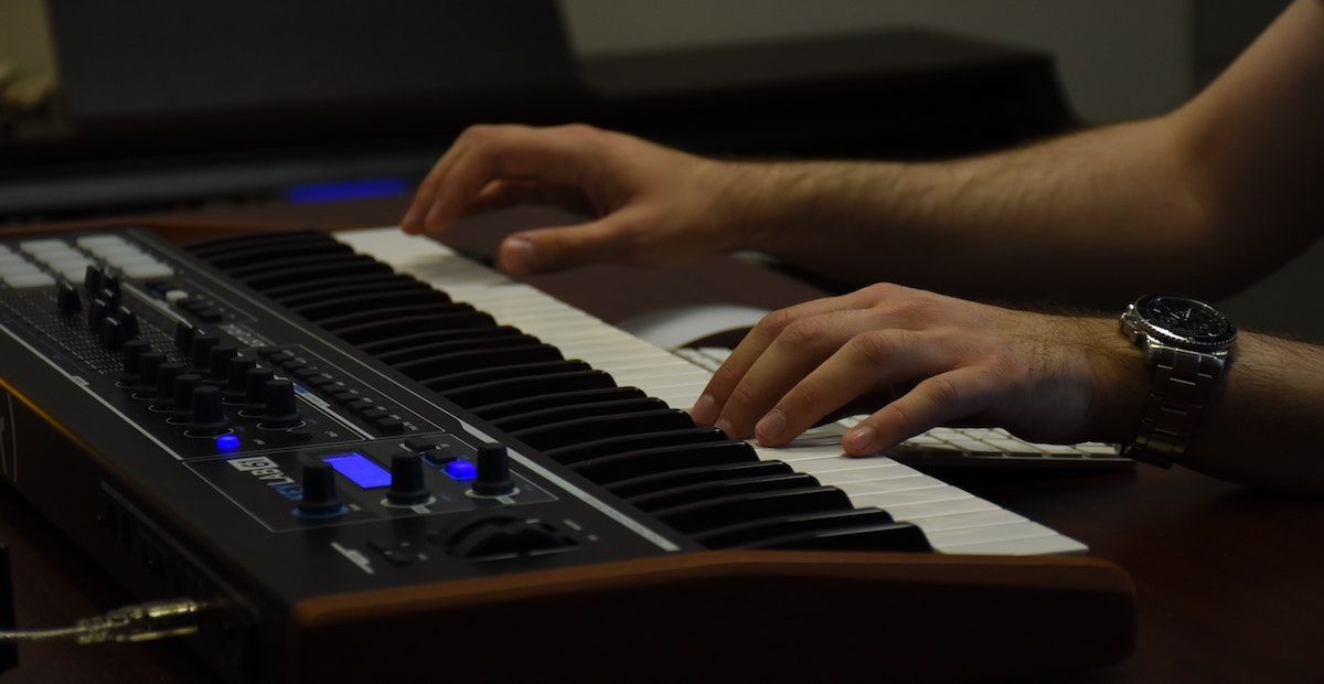 A person playing a keyboard wearing a watch