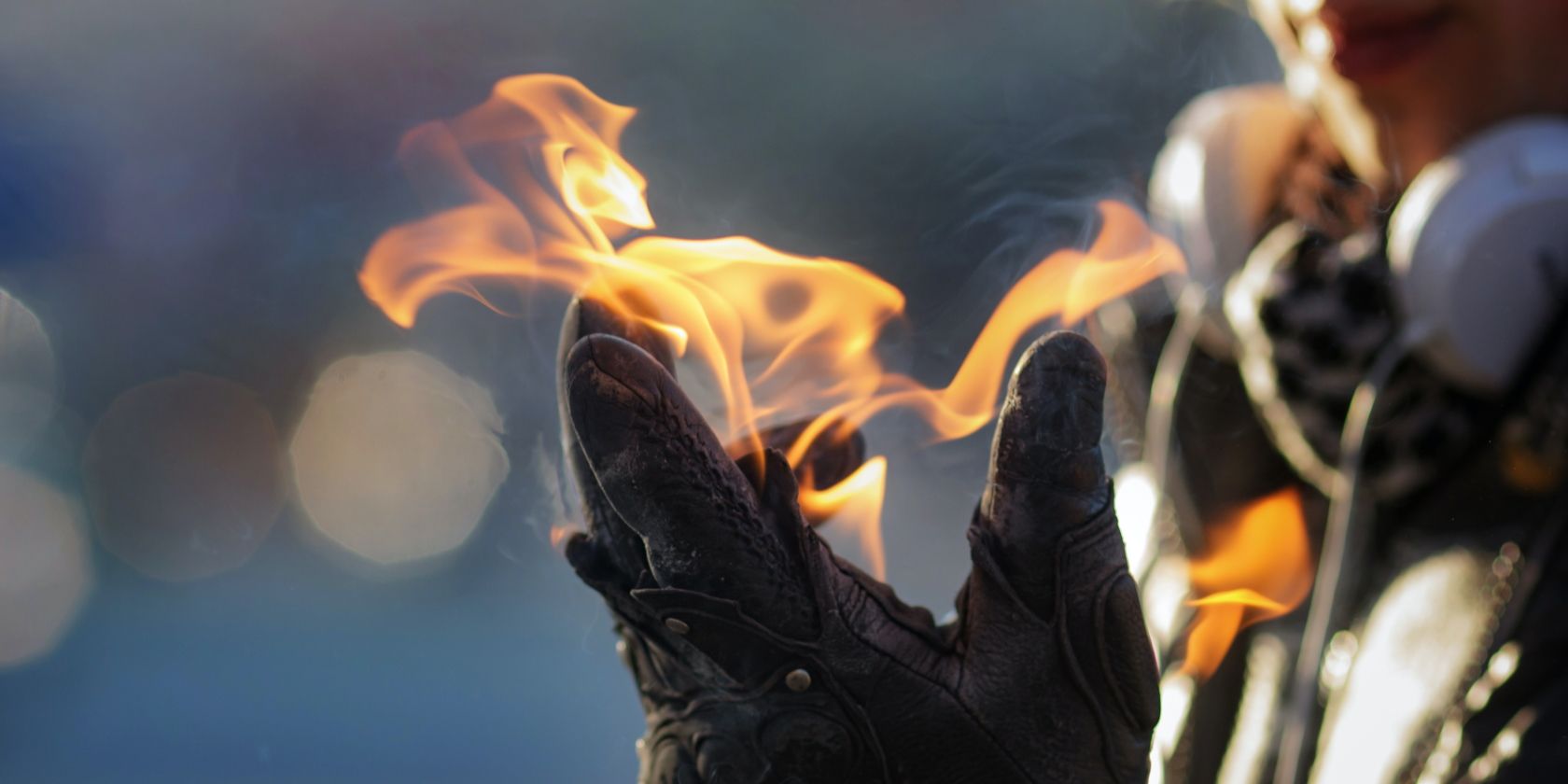 a person weraing headphones holds fire in a gloved hand