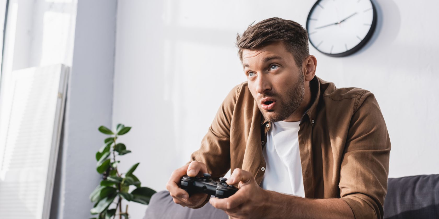 Man holding PlayStation controller, engaged in a game