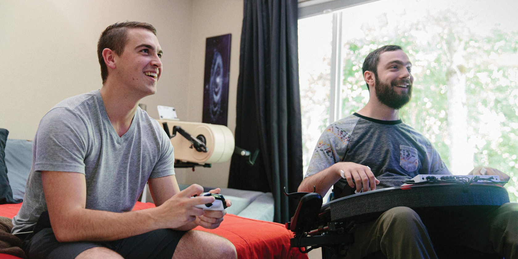 a man in a wheelchair and his friend playing xbox