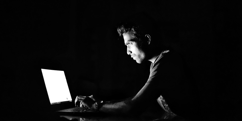 Man uses a laptop in the dark