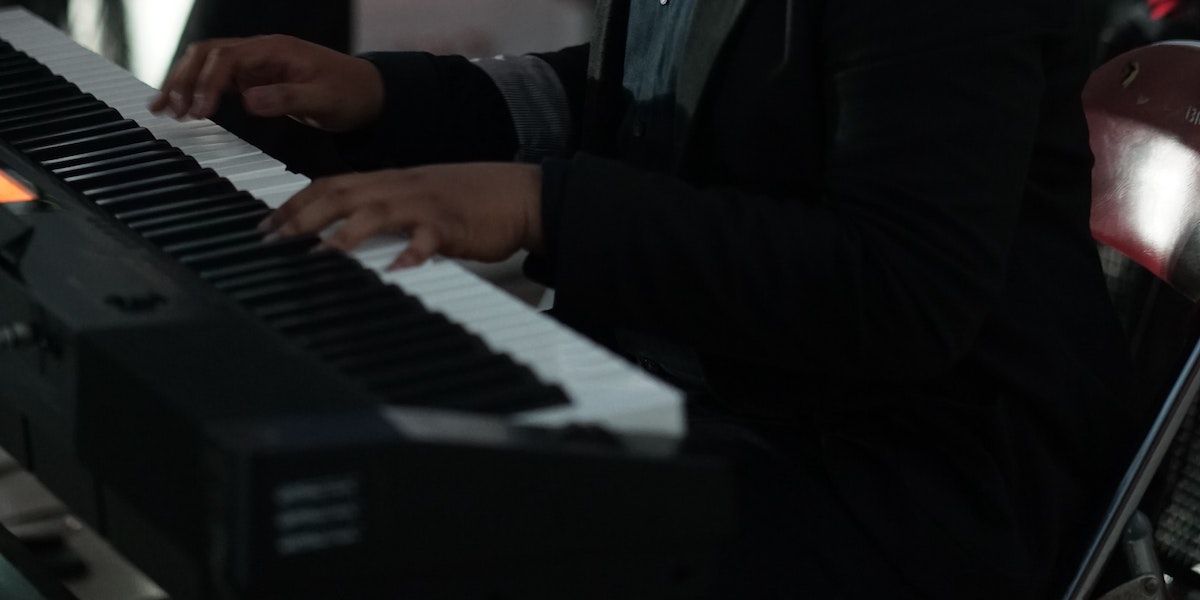 Person playing keyboard wearing a black coat.