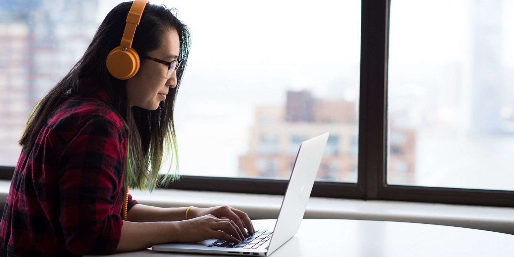 Woman wearing headphones and using a laptop