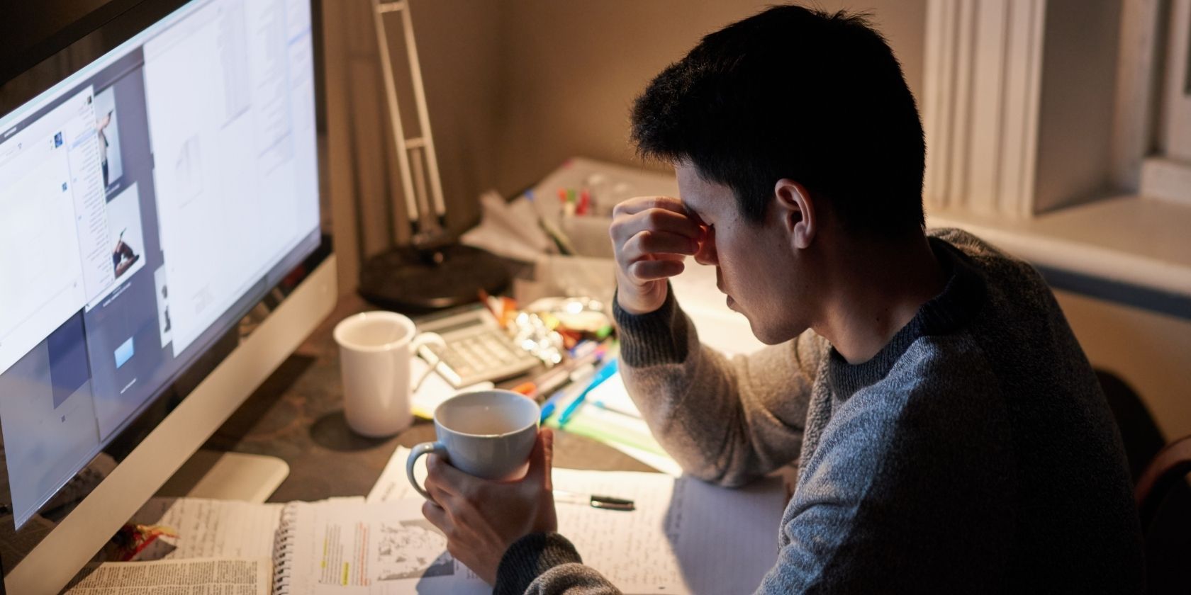 Student completing work at desk looking stressed