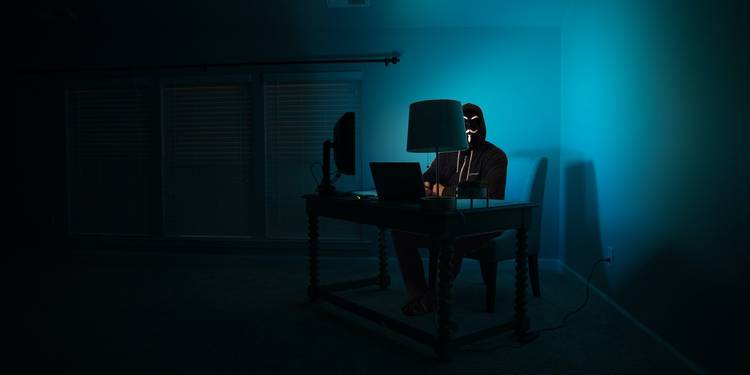 نحوه هک شدن گوشی شما از راه دور و روشهای پیشگیری از آن 2 hacker sitting with laptop.jpg?q=50&fit=crop&w=750&dpr=1 -