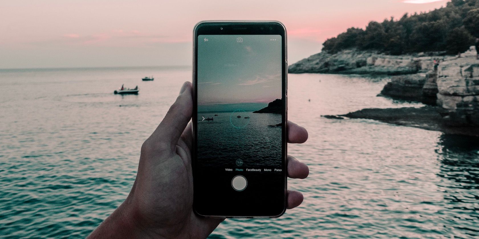 Person taking photo of sea on an iPhone.
