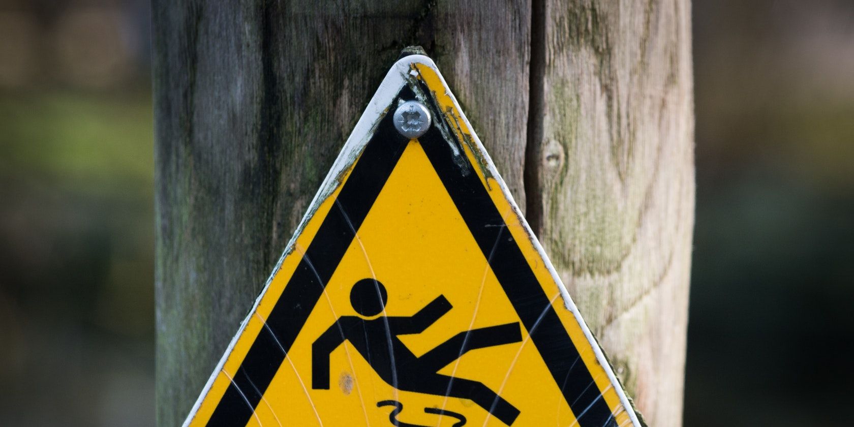 Triangular warning sign with an image of a person falling over.