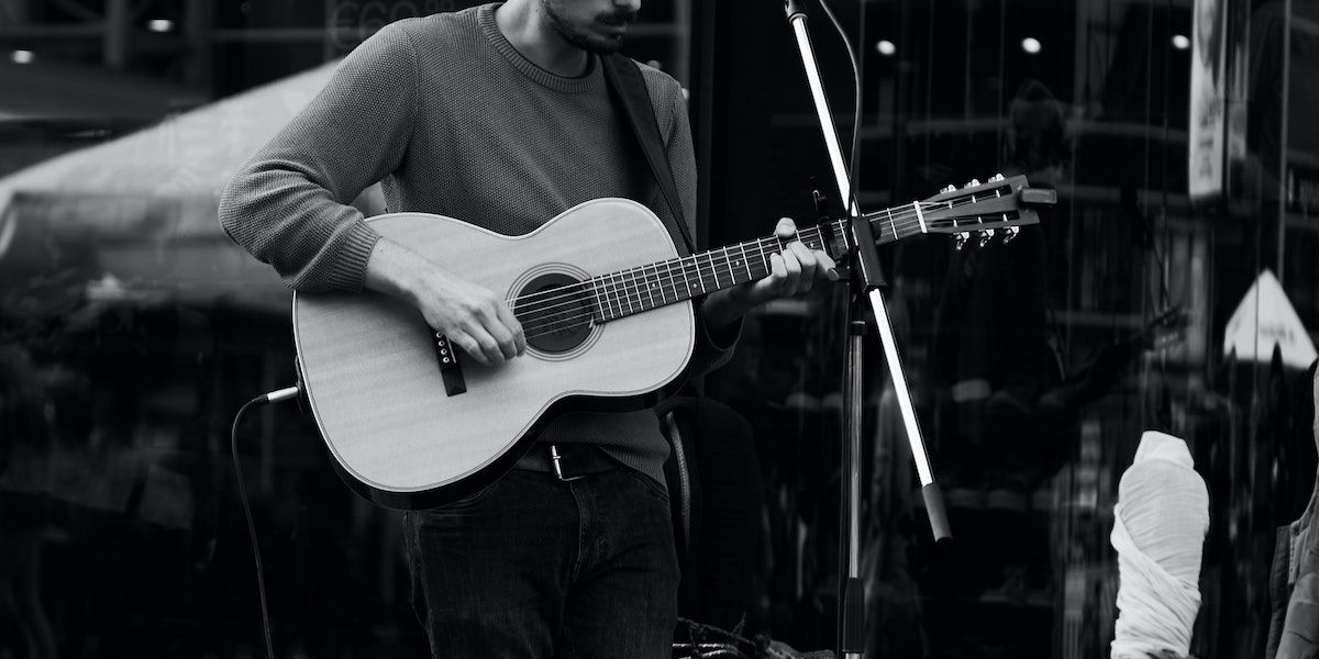 A person playing an electro-acoustic guitar live.