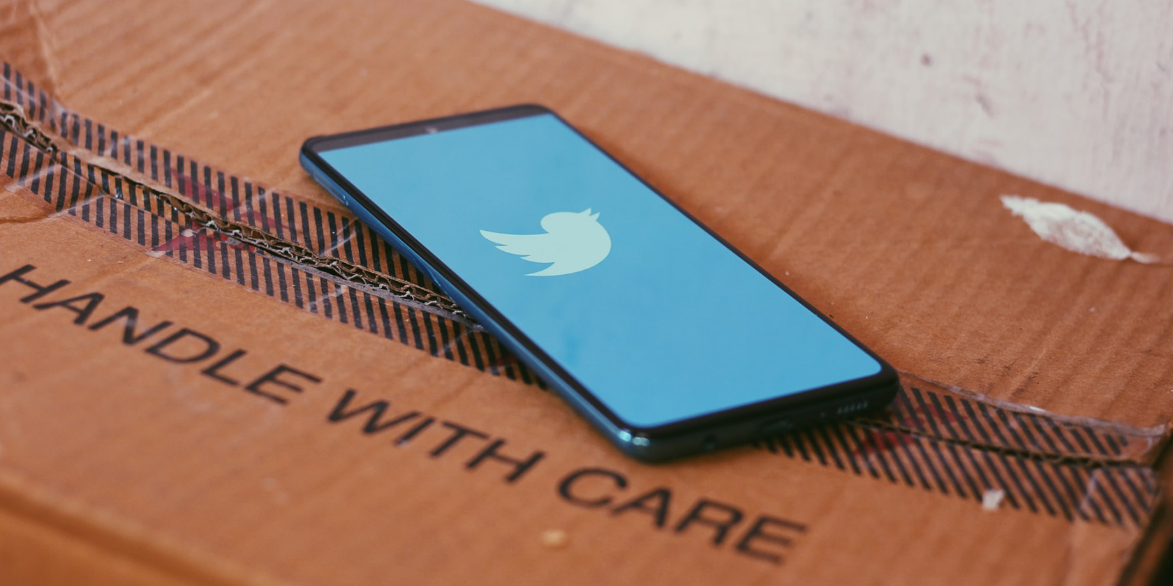 A smartphone on top of a cardboard box with the Twitter app open