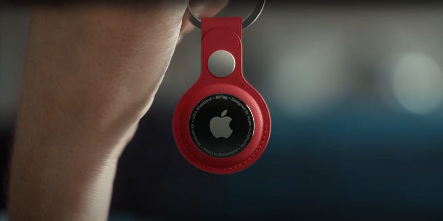 A still from Apple's ad for the AirTag item tracker showing a hand holding a keychain with an AirTag attached to it