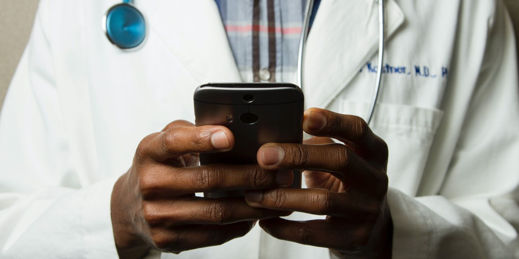 A doctor in a white coat looking at a smartphone
