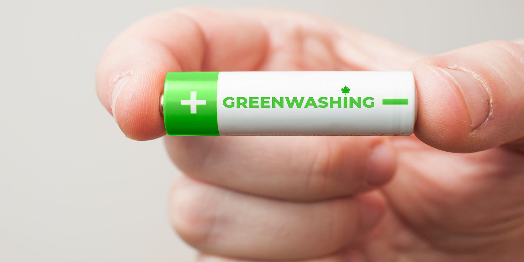 Person holding a battery with the phrase greenwashing
