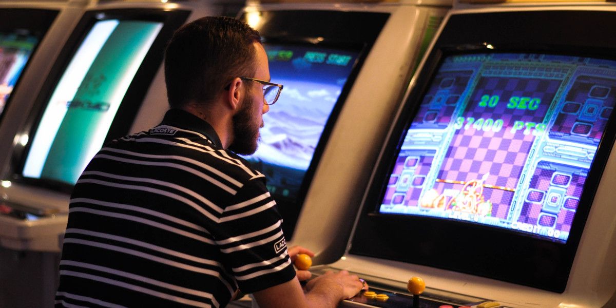guy playing puzzle bobble arcade cabinet - Che cos’è GaaS (Games as a Service) e in che modo influisce sul gioco?