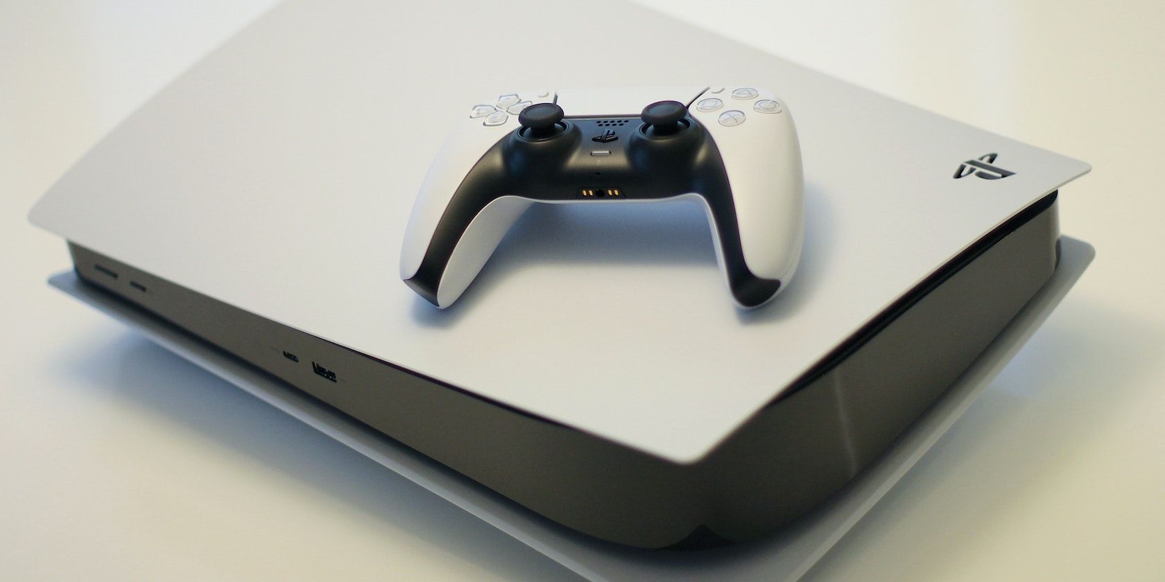 A PS5 on its side with a DualSense controller on it.