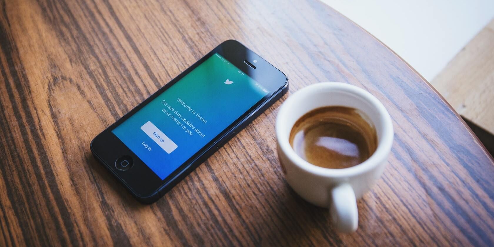 A cup of coffee and an iPhone on a table.