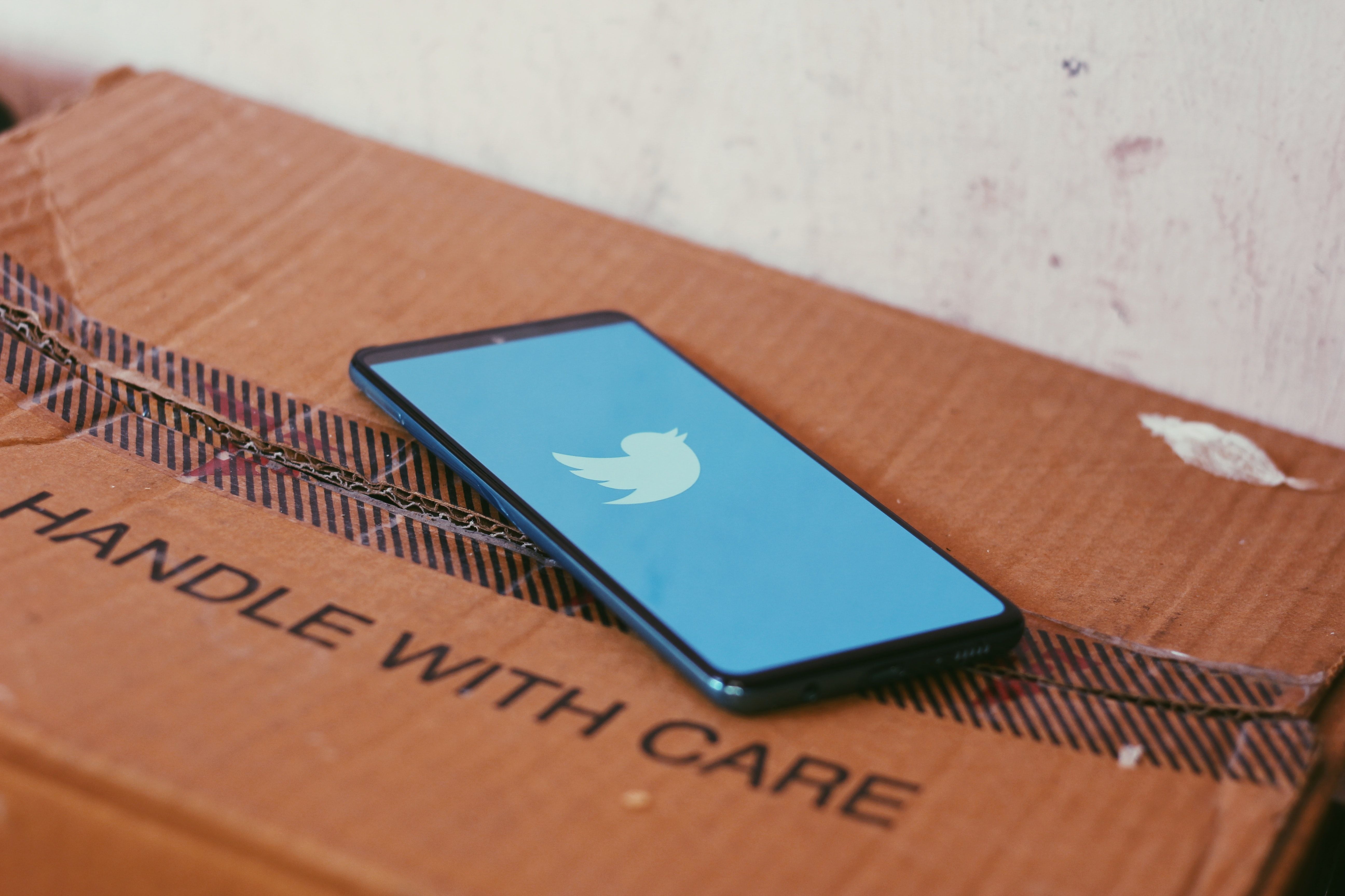 phone loading twitter on top of handle with care box