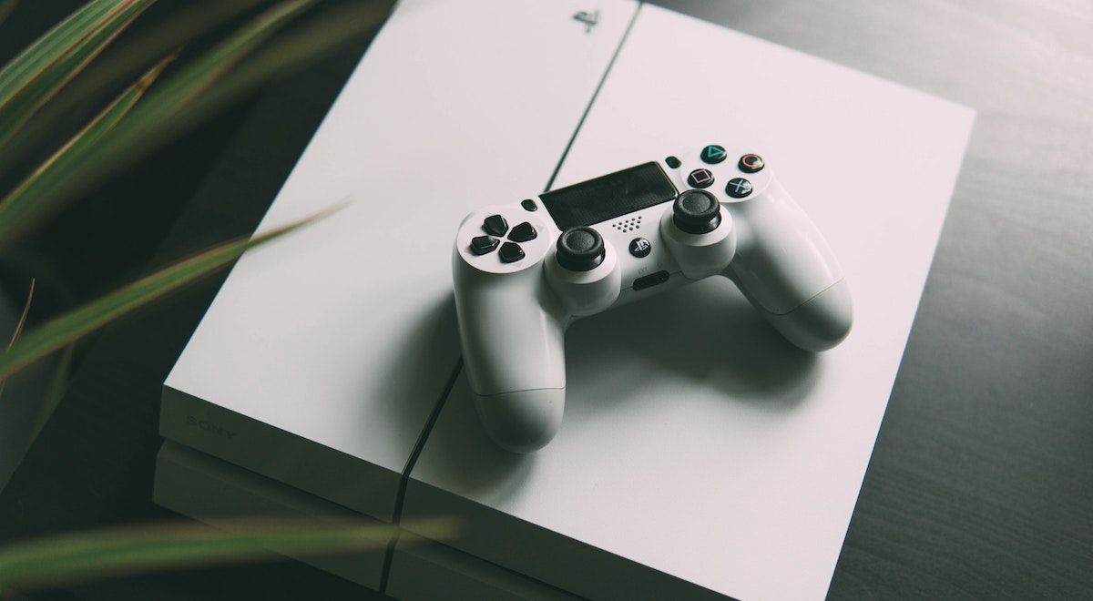 A white PS4 with a white PS4 controller on top of it.