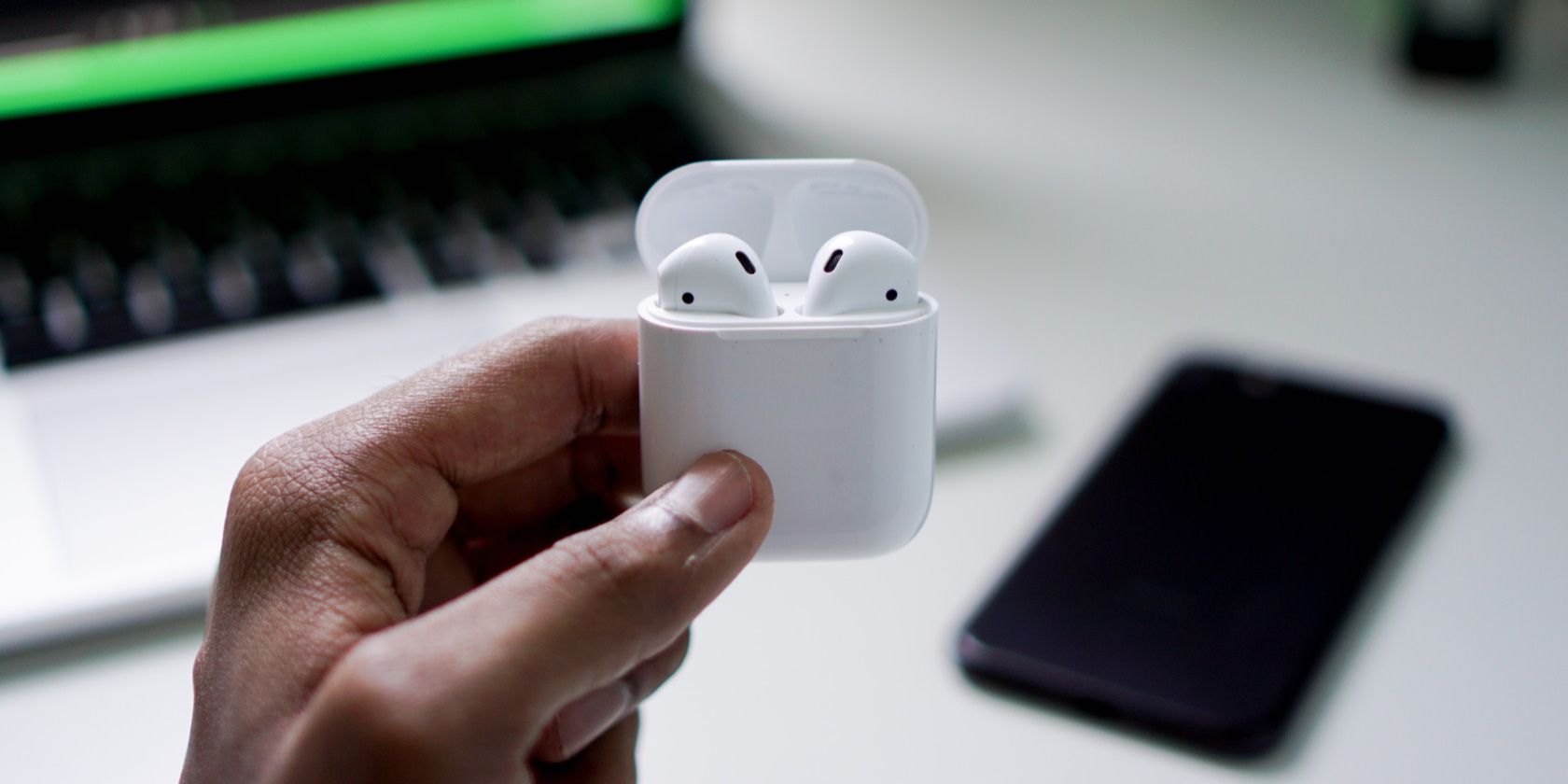 Person holds up AirPods in their case