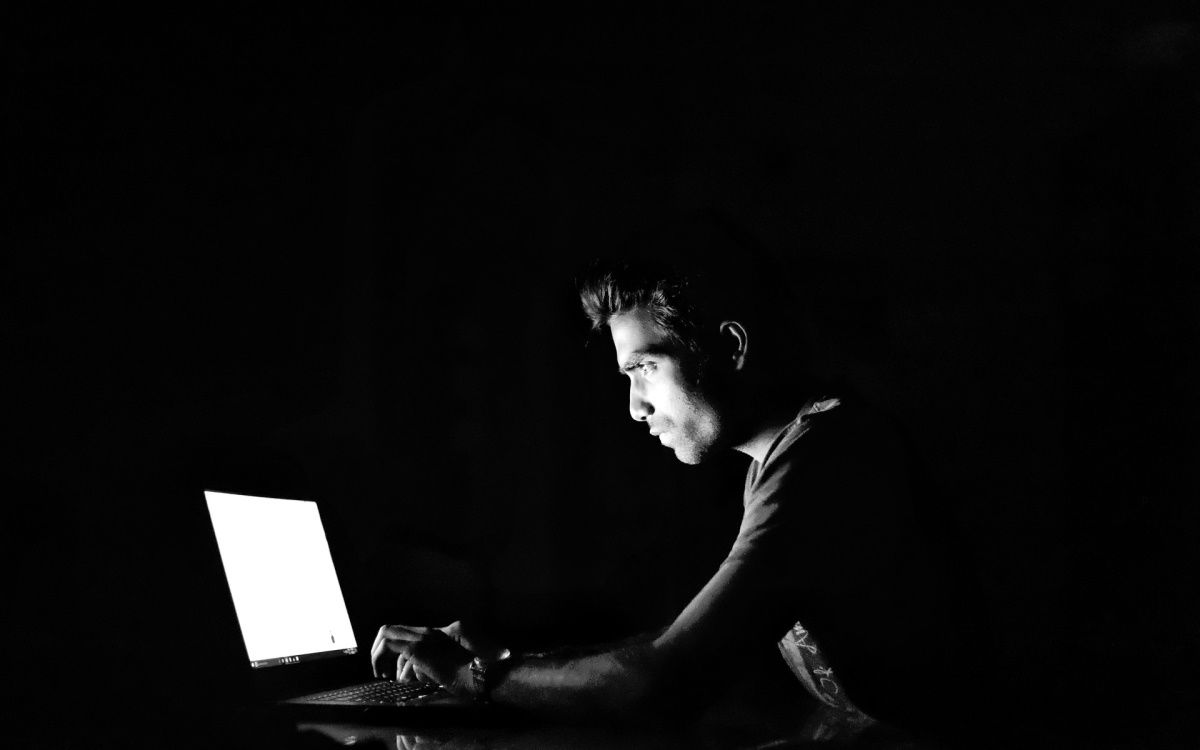 homem usando um laptop no quarto escuro