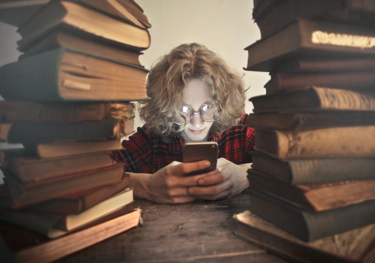 Two Book Stacks with Boy with Glasses on Phone in Centre