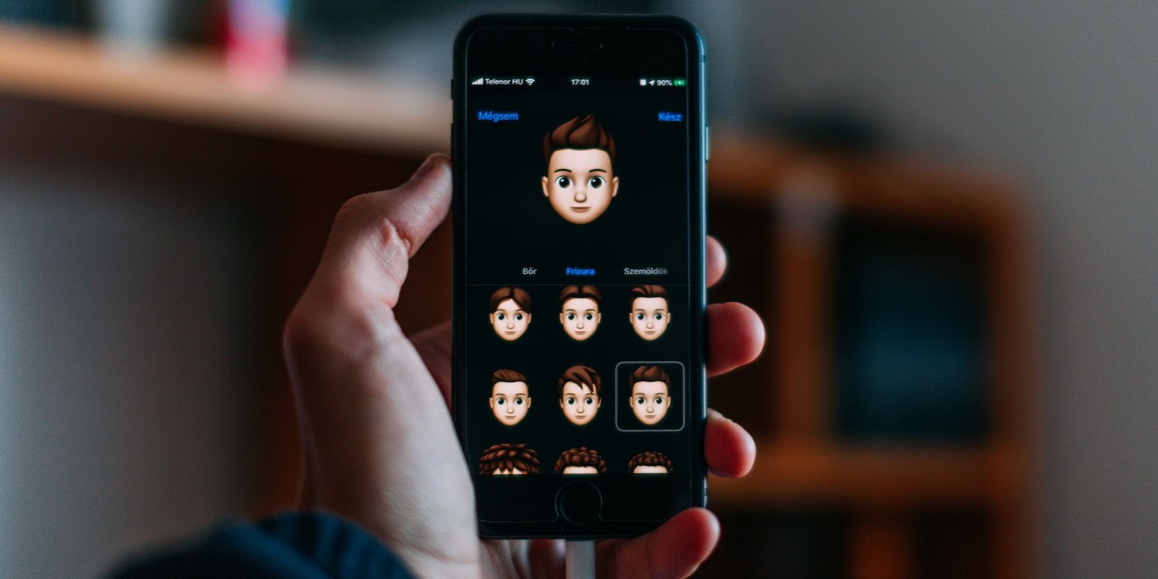 Hand holding iPhone to customize a Memoji