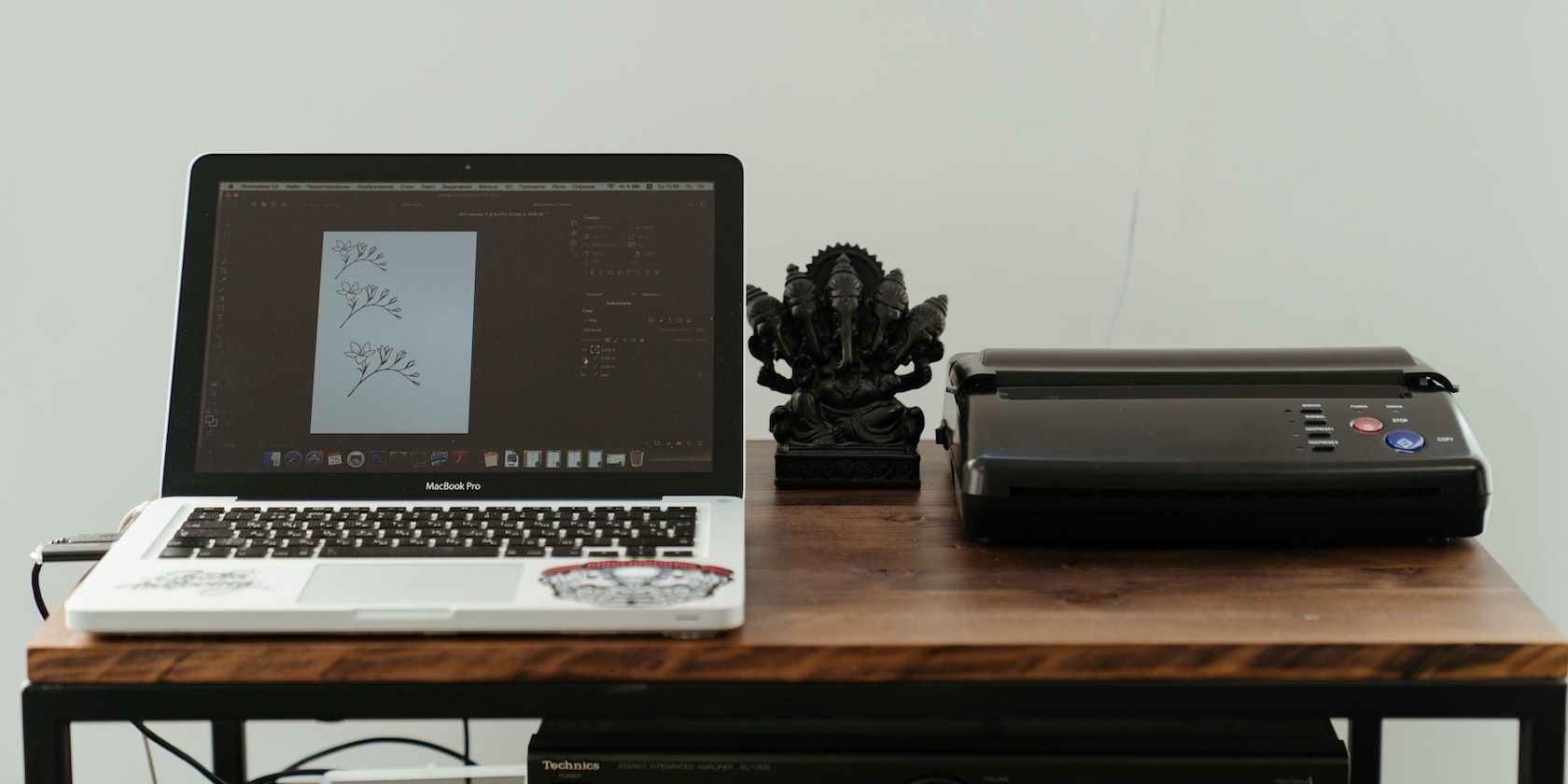 A printer sits beside a MacBook on a desk
